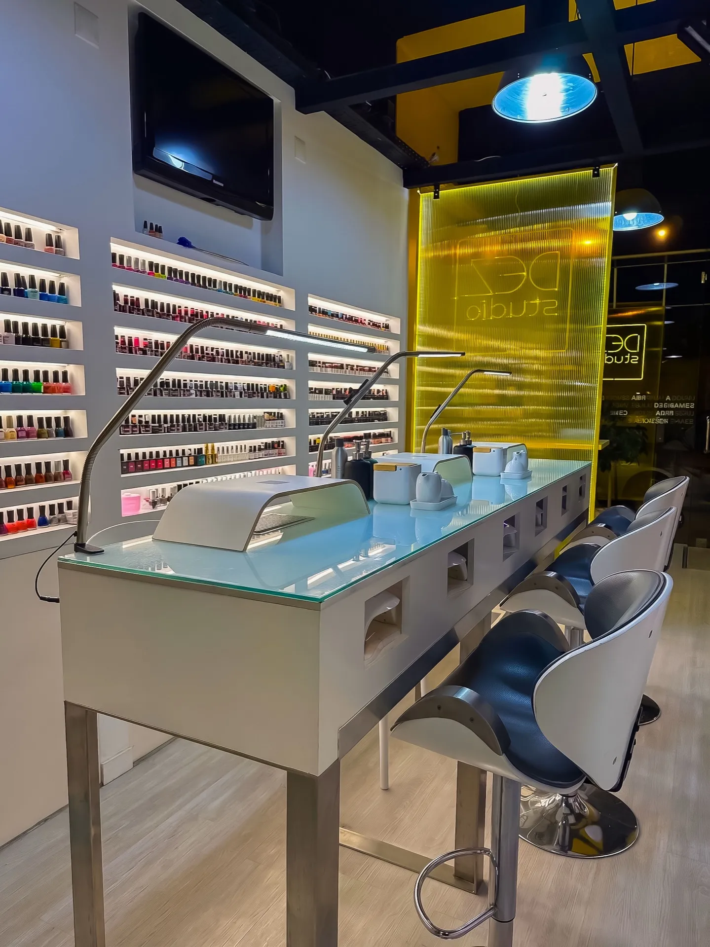 Bancada de manicura do Dezstudio em Filipa de Vilhena, com a parede de vernizes e o painel amarelo da marca
